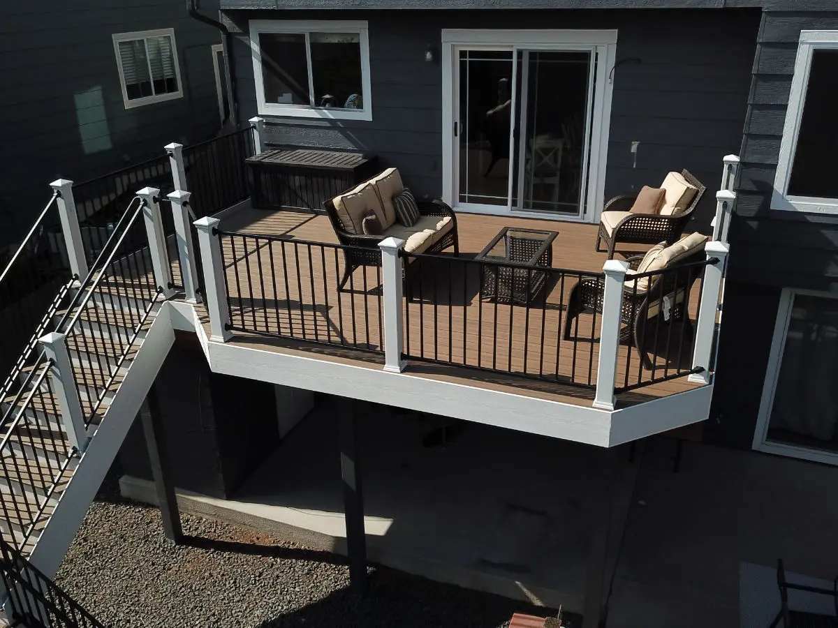 Raised deck seating area with white posts and black railing on a dark gray home