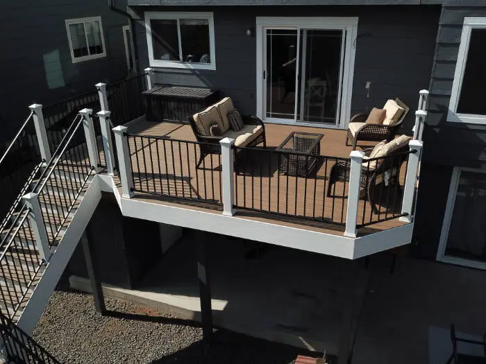 Aerial view of a raised deck with white railing and stairs on a dark gray home