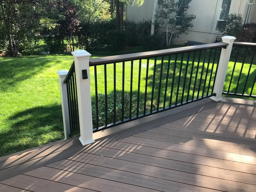 Composite deck with a white post and black balusters beside a lawn